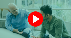 The empathetic mature adult man gestures and asks questions as he helps the younger man work through his problems. |