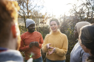 A multiracial group of volunteers wearing warm casual clothing and accessories on a sunny cold winters day. They are talking before they start working on a community farm, planting trees and performing other tasks. |