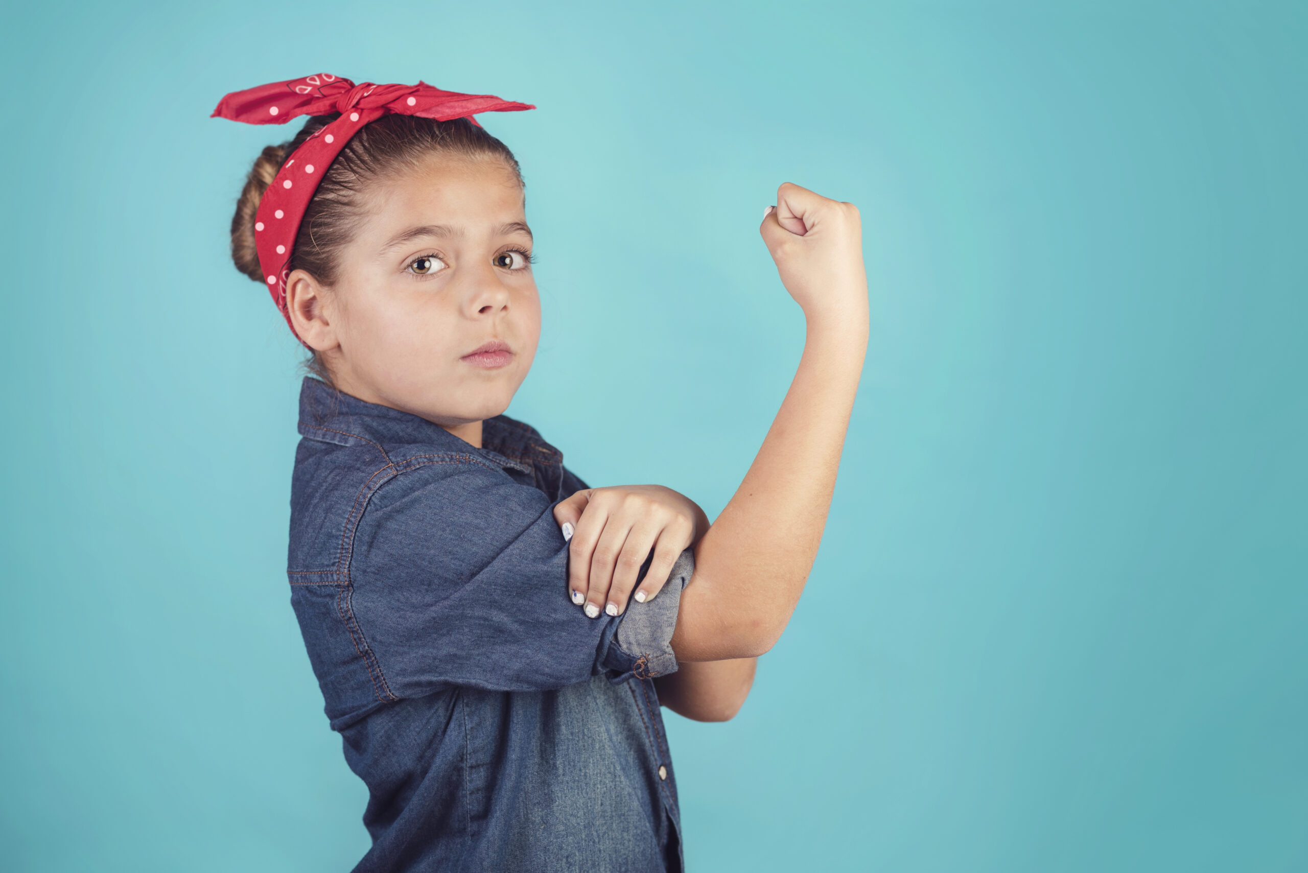 Child dressed as Rosie the Riveter on blue background