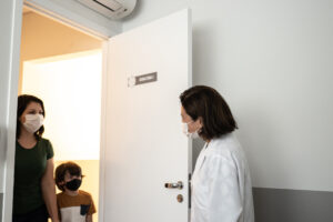Doctor welcoming patient into her office - wearing protective face mask |