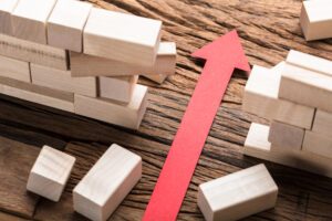 High angle view of red paper arrow amidst blocks on wooden table |