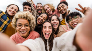 Multiracial friends taking big group selfie shot smiling at camera - Laughing young people standing outdoor and having fun - Cheerful students portrait outside school - Human resources concept |