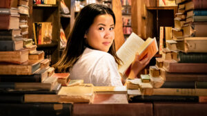 woman in the library looks back over her shoulder as he reads a book