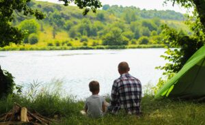 Father and a son sitting on the river bank.