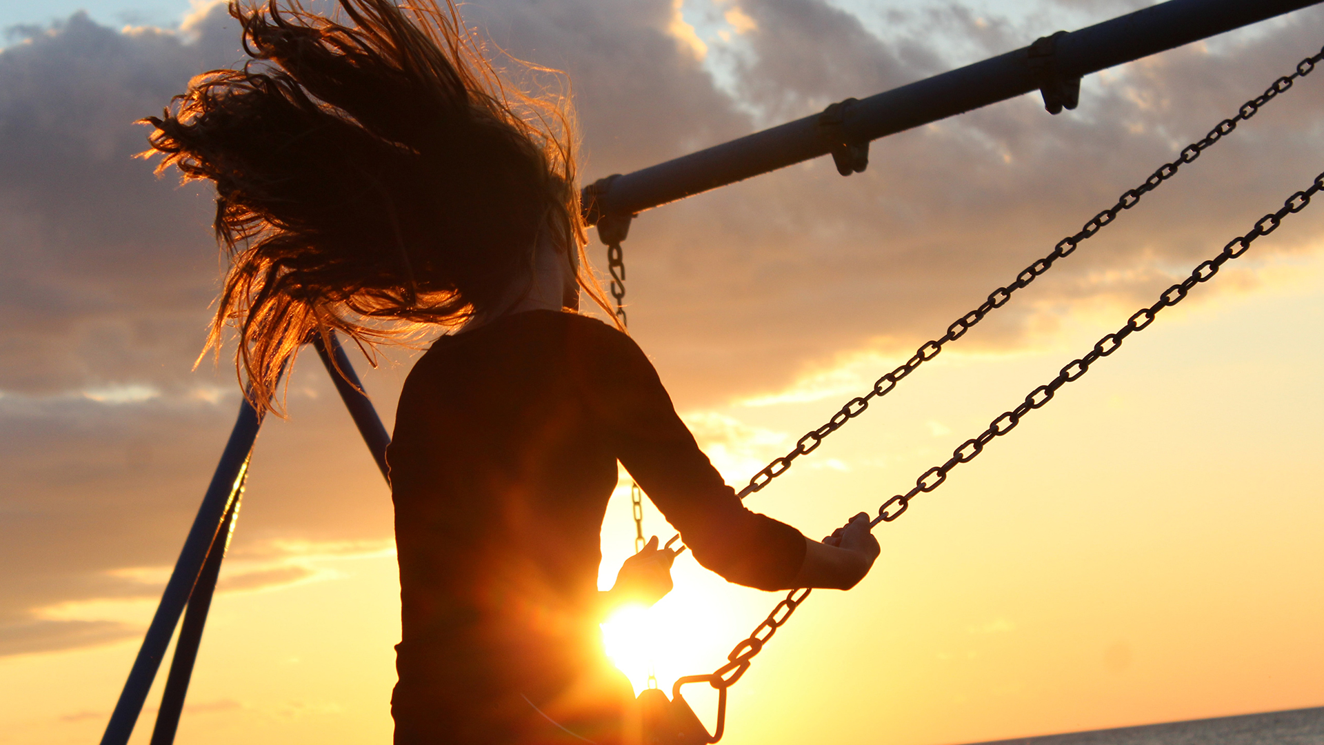 Woman flying on the swings at Sunset