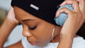 Young woman weaing a bennie puts on headphones