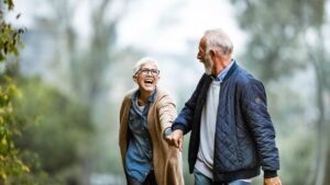 Mature couple walks in a park holding hands and smiling at each other