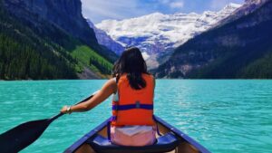 A women in a life west pedals in kanoo across the lake