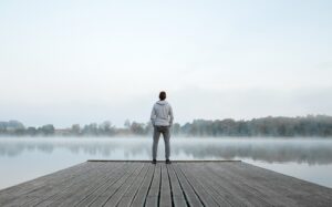 Young man standing alone on wooden footbridge