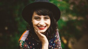 La jeune femme dans un chapeau noir sourit pendant qu'elle regarde dans l'appareil-photo