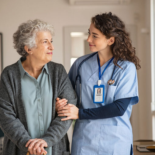 Young caregiver helping senior woman walking. Nurse assisting her old woman patient at nursing home. Senior woman with walking stick being helped by nurse at home.
