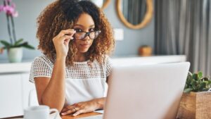 African-American woman lowered her glasses as she sat in front of her computer in a home office