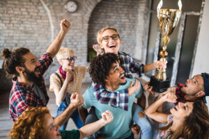 Large group of happy creative people celebrating getting a trophy at casual office. |