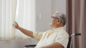 man in wheelchair looks out window