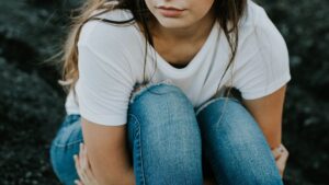 Gros plan d'une femme en jeans et chemise blanche assise sur le sol