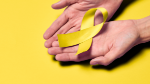 Les mains d'une personne tenant un ruban jaune sur fond jaune.