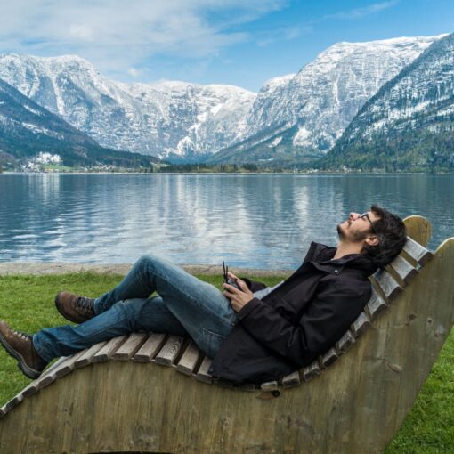 Un homme est assis sur une chaise en bois devant un lac.