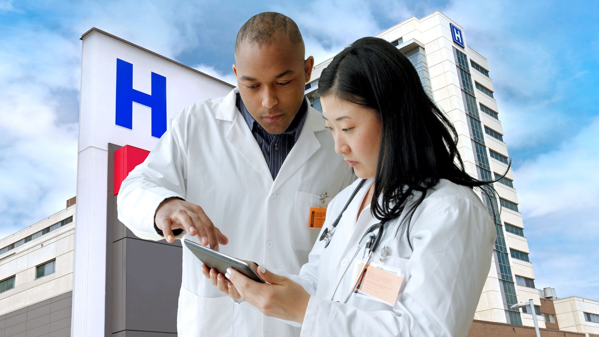 Un homme et une femme en blouse blanche examinant un comprimé, discutant éventuellement d'informations médicales.