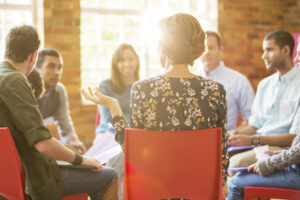 A diverse group of individuals sitting in chairs, engaged in a meeting to discuss important matters.