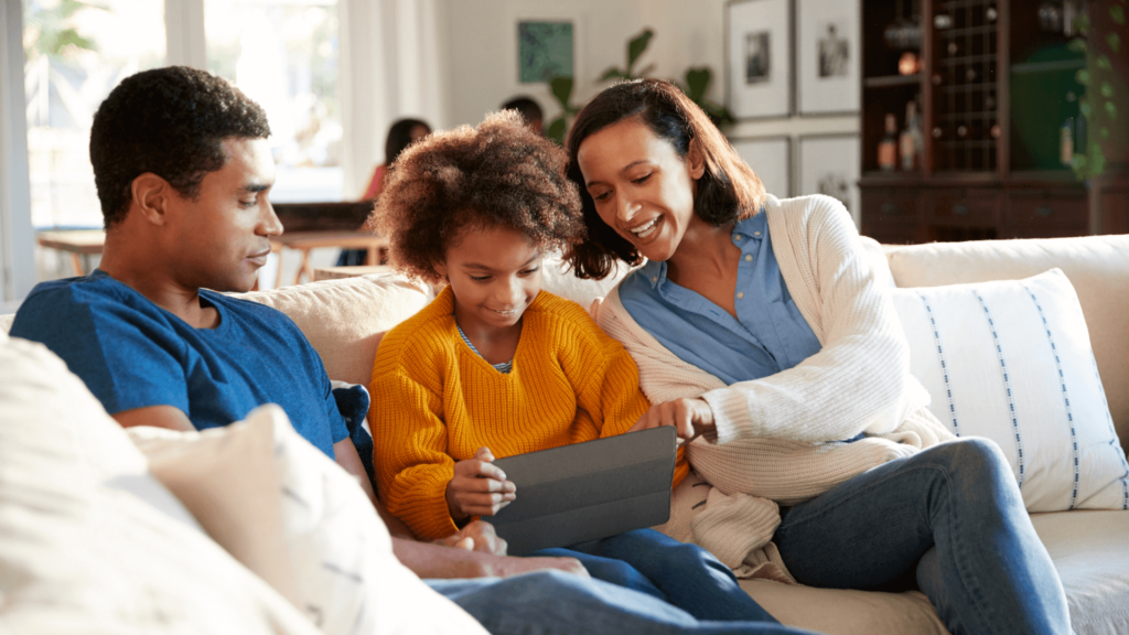 des parents qui regardent par-dessus l'épaule de leur enfant lorsque celui-ci utilise un iPad