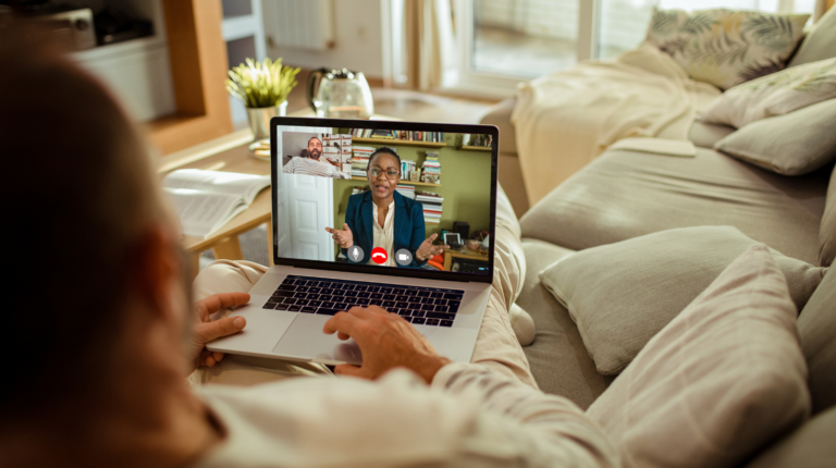 A man sitting on a couch with a laptop on the table.