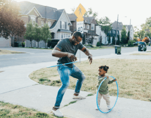 A parent and their child playing in their front yard