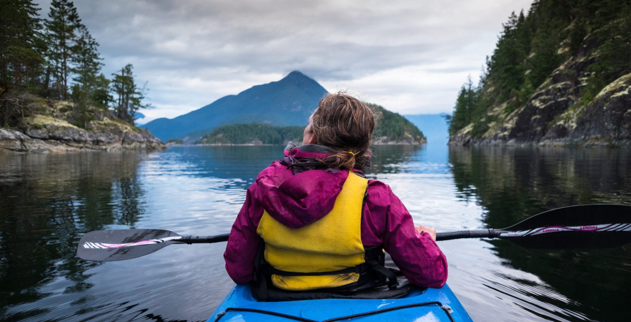 une femme en kayak profitant de la nature sur un lac immobile
