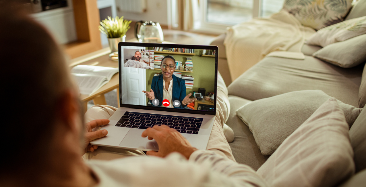 A man sitting on a couch with a laptop on the table.