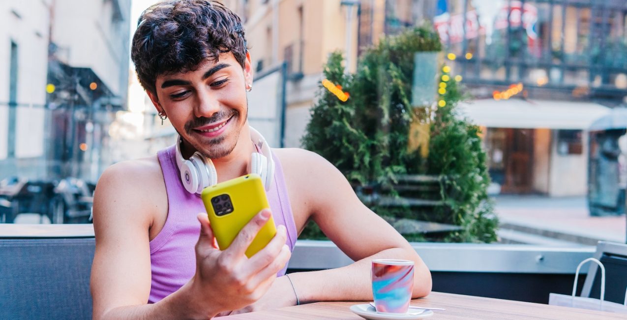 Un jeune homme utilisant un téléphone portable alors qu’il était assis à une table extérieure.